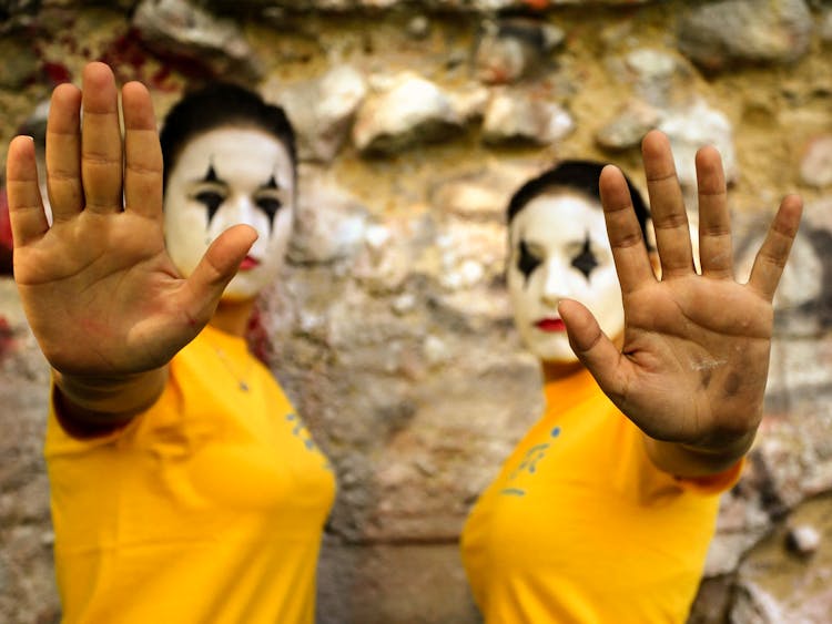 Photo Of Two Women With Painted Faces Raising Their Hands In An Act Of Objection