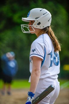 Young female softball player ready to bat during a game in an outdoor field.
