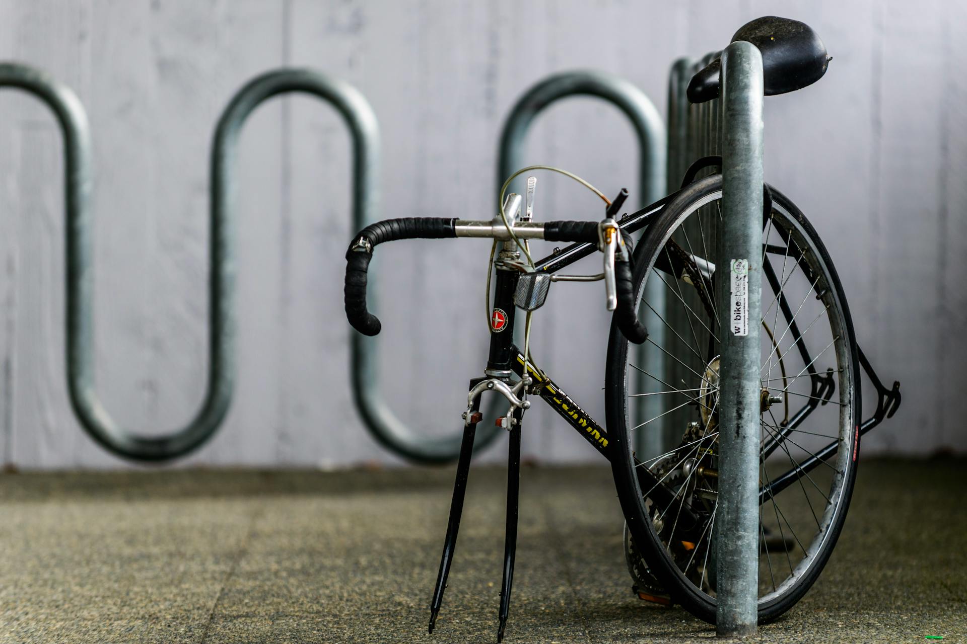 A bicycle parked at a metal rack, emphasizing urban transportation security.