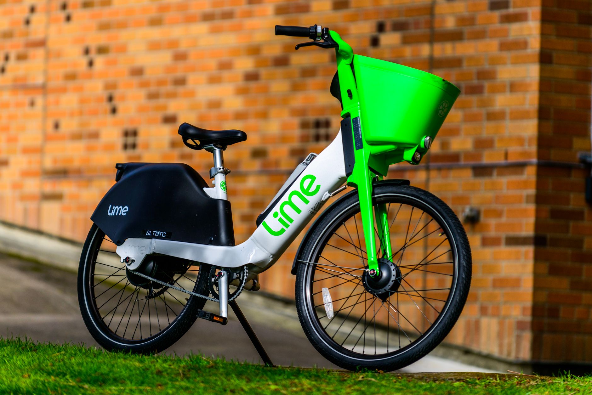 Vibrant Lime e-bike parked outdoors against a brick wall, showcasing modern transportation.