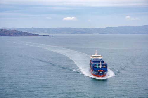 Free A cargo ship filled with containers travels across calm ocean waters on a clear day. Stock Photo
