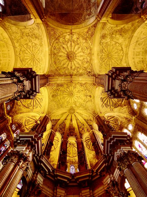 Free Vertical view of the ornate ceiling and pillars inside a Spanish cathedral showcasing architectural grandeur. Stock Photo