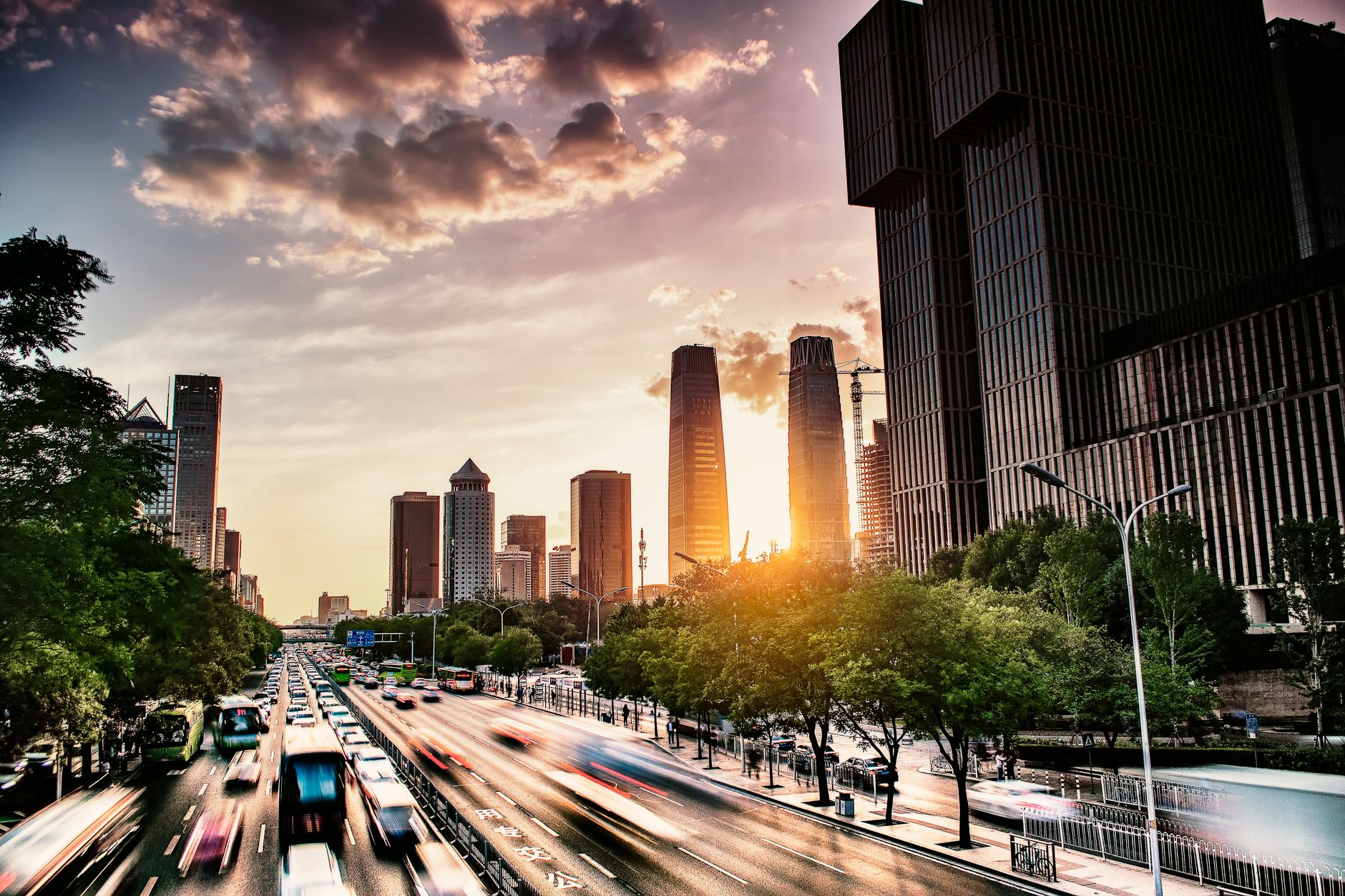 A dynamic view of Beijing's skyline with traffic and skyscrapers at sunset.