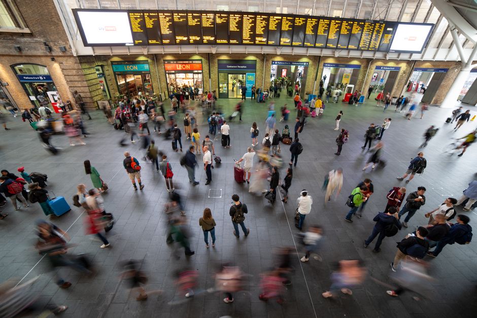 A bustling scene at King's Cross Station in London with travelers and blurred motion.