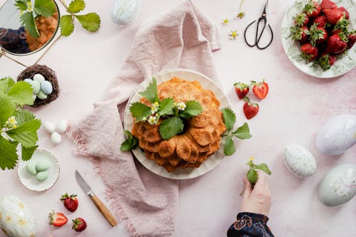 Hand Decorating a Dessert and Strawberries on a Table 