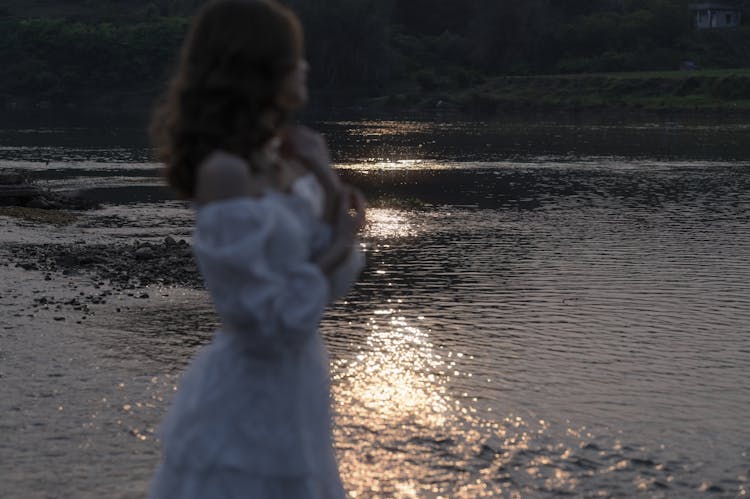 Woman Standing On Shore With Sunshine Reflecting On Water