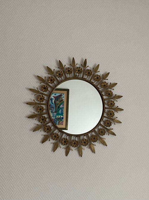 Free A decorative sunburst mirror reflecting colorful abstract artwork on a neutral wall. Stock Photo