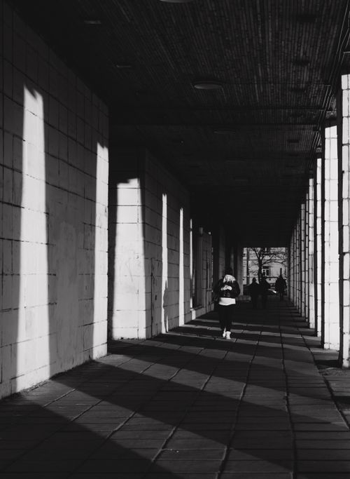 Free Dramatic black and white photo of a person walking through an urban walkway. Stock Photo