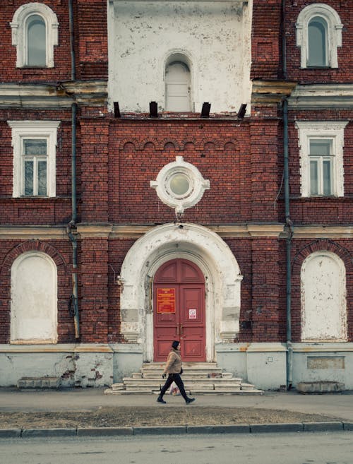 A Woman Walking in Front of an Old Building