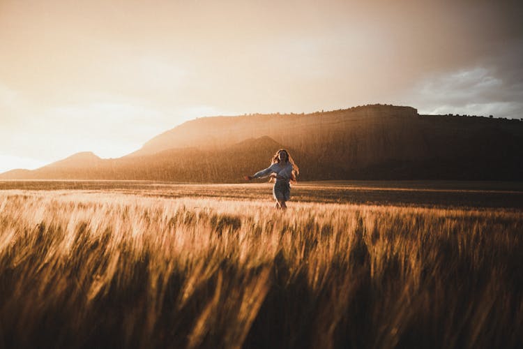 Woman Running Through A Field At Sunset