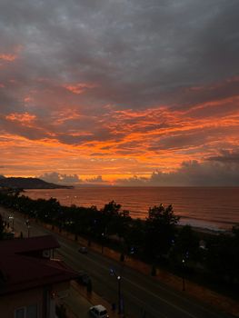Stunning orange sunset over a seaside road with a vibrant sky and calm ocean waves.