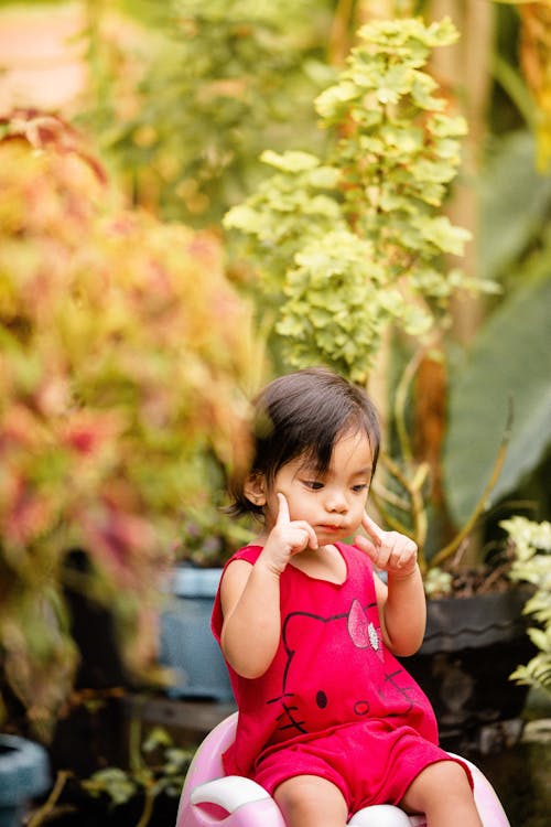 Free Girl in Pink Tank Top Standing Near Green Plants Stock Photo