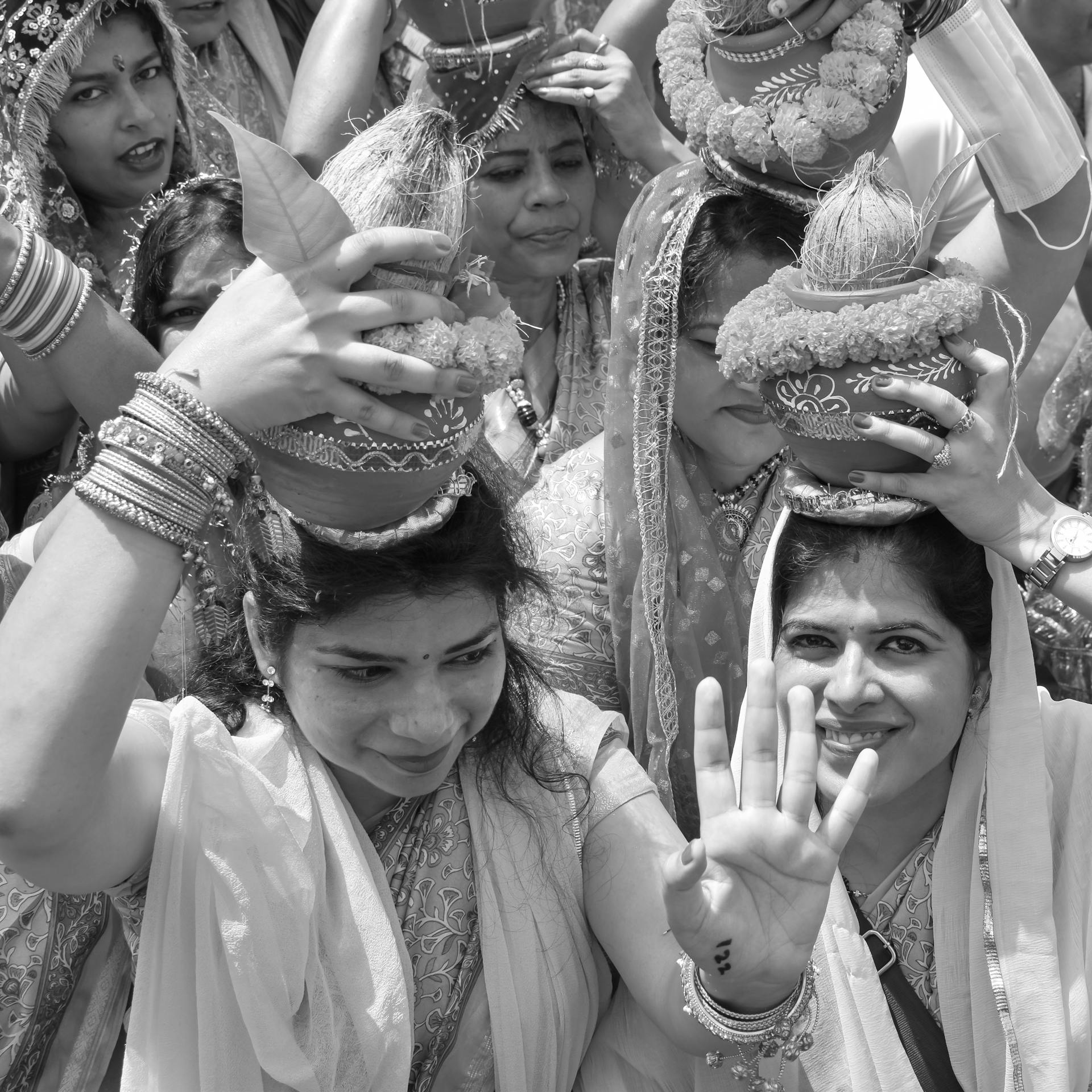 A group of women celebrate a traditional festival, carrying clay pots and adorned in cultural attire.