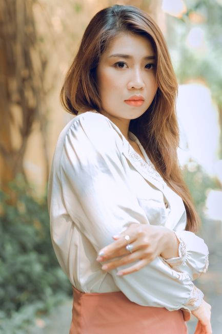 Stylish outdoor portrait of a young Asian woman in a white blouse, exuding elegance and confidence.