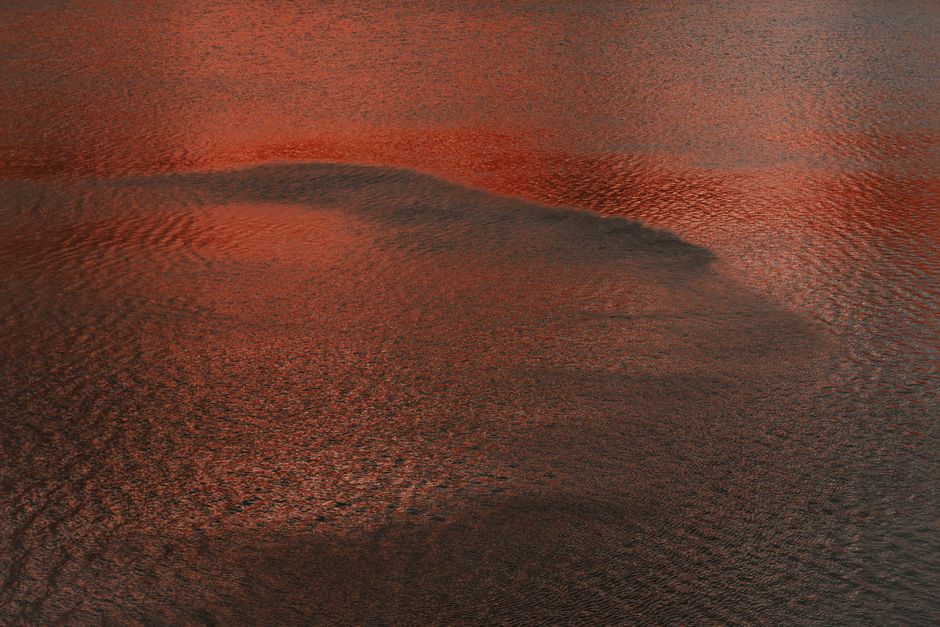 Red-tinted water surface with ripples creating a serene abstract pattern.