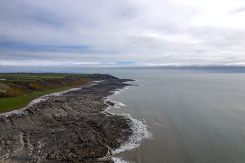 An Aerial Shot of a Coast under a Cloudy Sky