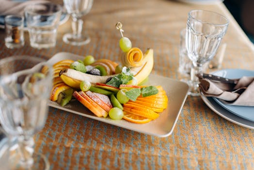 A beautifully arranged fruit platter featuring various fresh fruits elegantly displayed on a dining table.