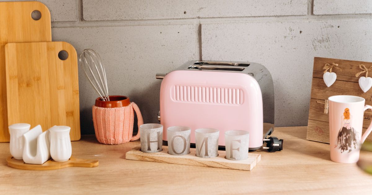 A pink two-slice toaster on a wooden kitchen countertop