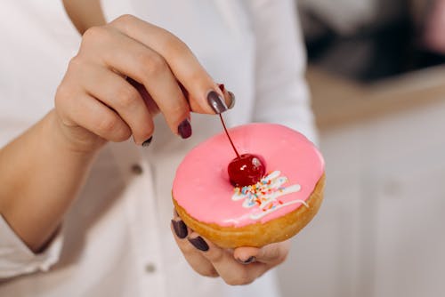 Free A Person Holding a Doughnut and a Cherry  Stock Photo