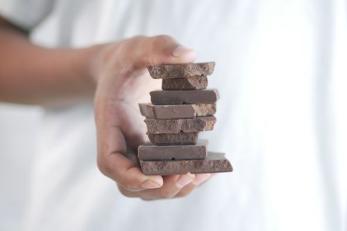 Free Close-up of a hand holding a stack of chocolate bars with a soft background. Stock Photo