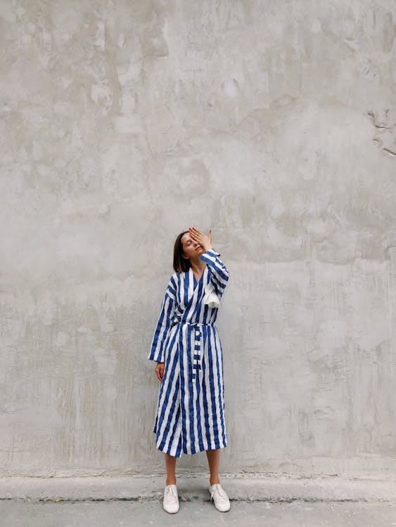 Woman in Blue and White Striped Dress Covering Her Left Eye