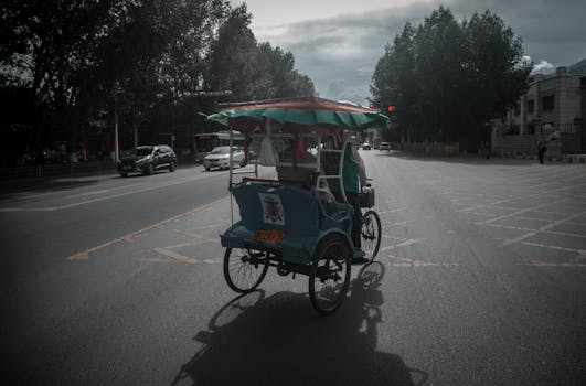 A colorful tricycle approaches an intersection on a street in Tibet, China, during the day.