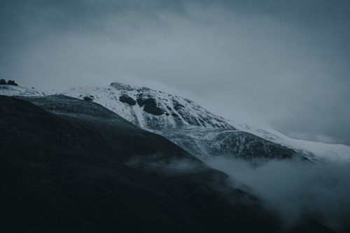 Free Captivating view of a snow-covered mountain peak shrouded in mist and dark clouds in Tibet. Stock Photo