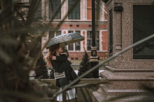 Elegant woman with umbrella posing by vintage building in London.