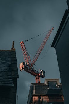 Low-angle view of a tower crane amidst buildings under construction in Oxford, UK.