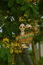 Woman in Red and Yellow Floral Long Sleeve Shirt Standing Beside Yellow Flowers