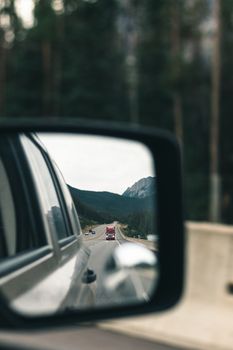 Captured highway view in a car mirror, showcasing travel and reflection.