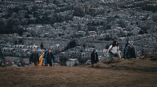 People Climbing a Hill and Cityscape in Background