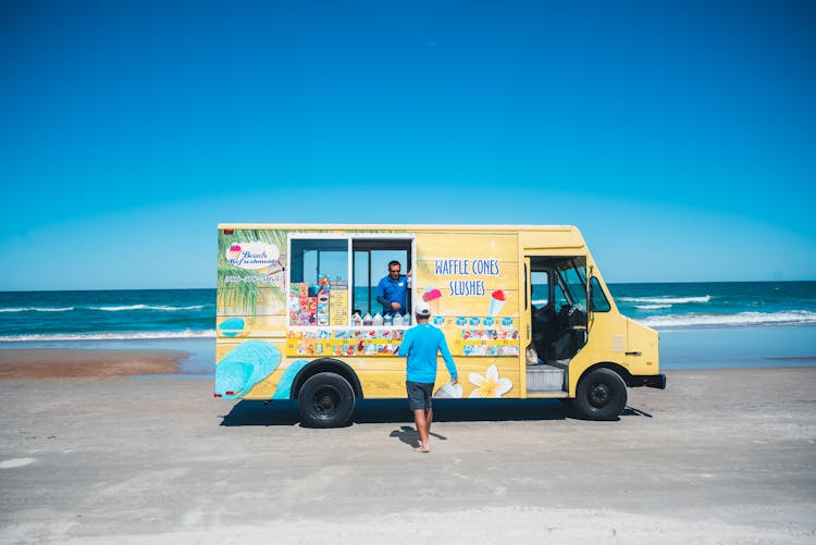 Man Walking Towards The Ice Cream Truck In The Beach