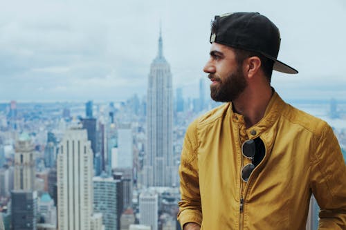 Foto Potret Pria Dengan Jaket Zip Up Kuning Dekat Empire State Building