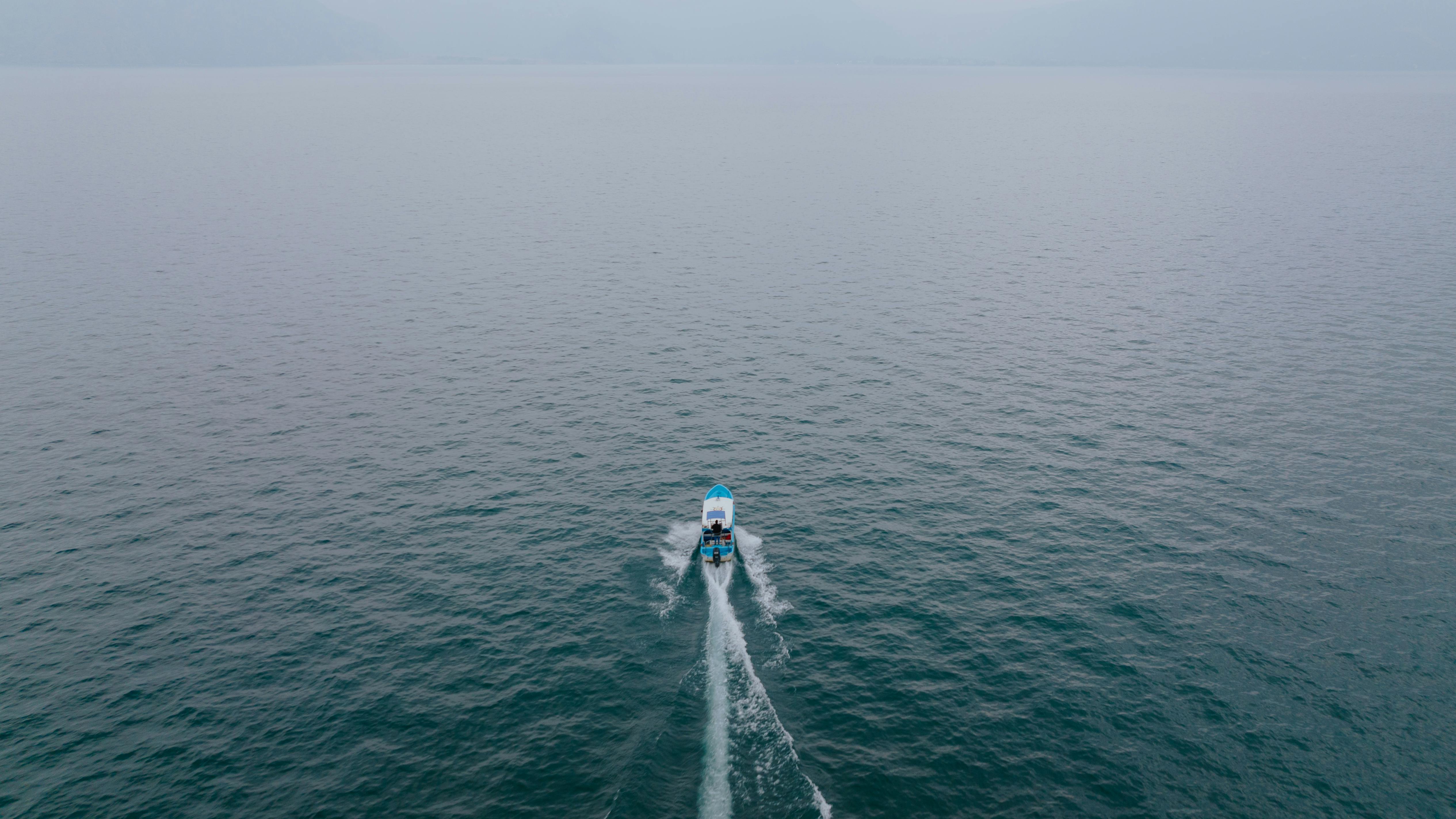 Free A solitary boat navigates a calm sea, captured from above, showcasing serene seascape. Stock Photo