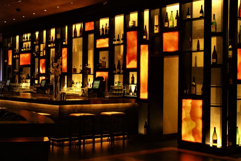 Elegant bar counter with backlit shelves displaying wine bottles and sparkling glassware