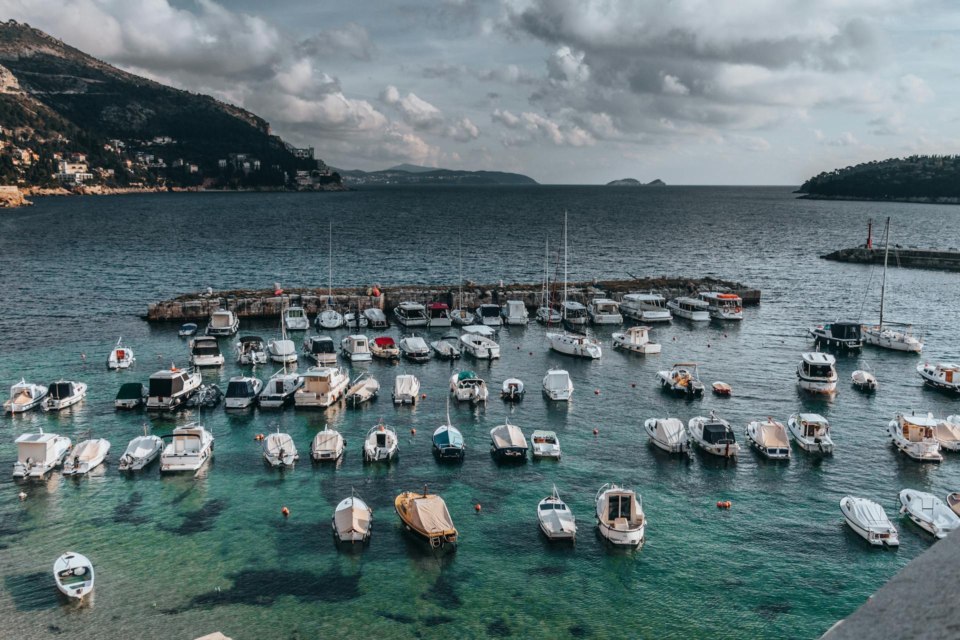 Aerial shot of yachts moored in Dubrovnik harbor, Croatia with cloudy skies.