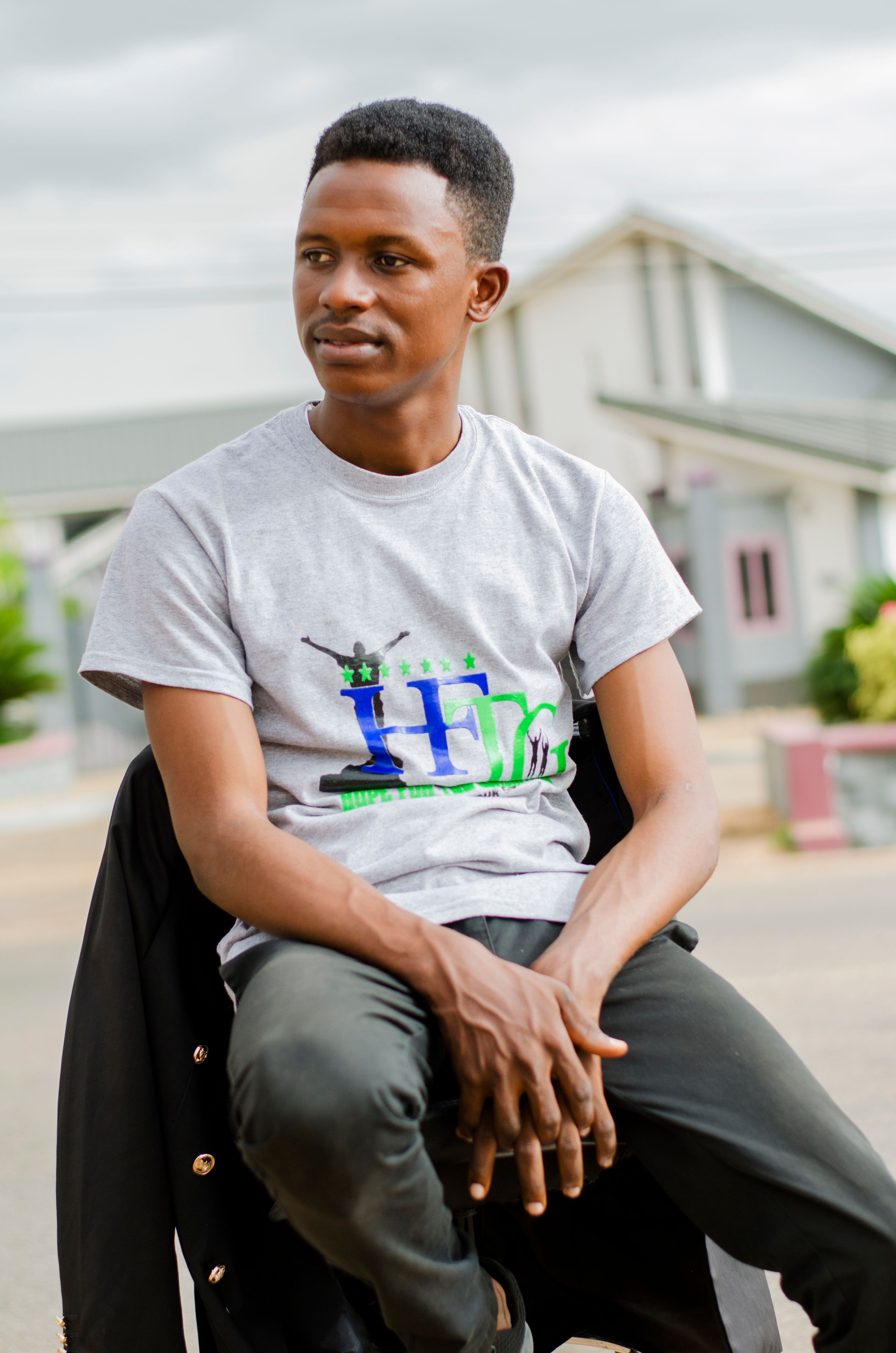 Portrait of a young man sitting outdoors in Ghana, wearing a casual t-shirt.