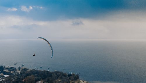 Free Aerial view of a paraglider cruising over the ocean with a scenic coastal landscape below. Stock Photo