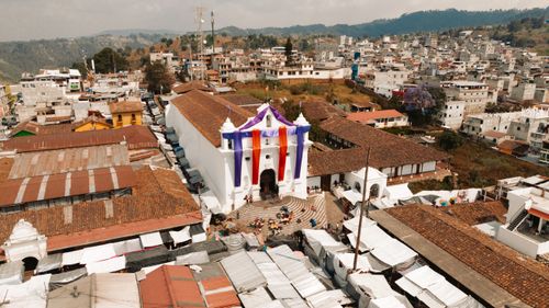Free Aerial view of a church decorated with colorful banners amidst a bustling urban town landscape. Stock Photo