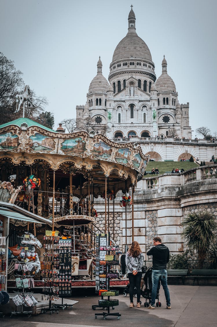 Family On A Park Beside A Carousel With View Of Basilica On Background