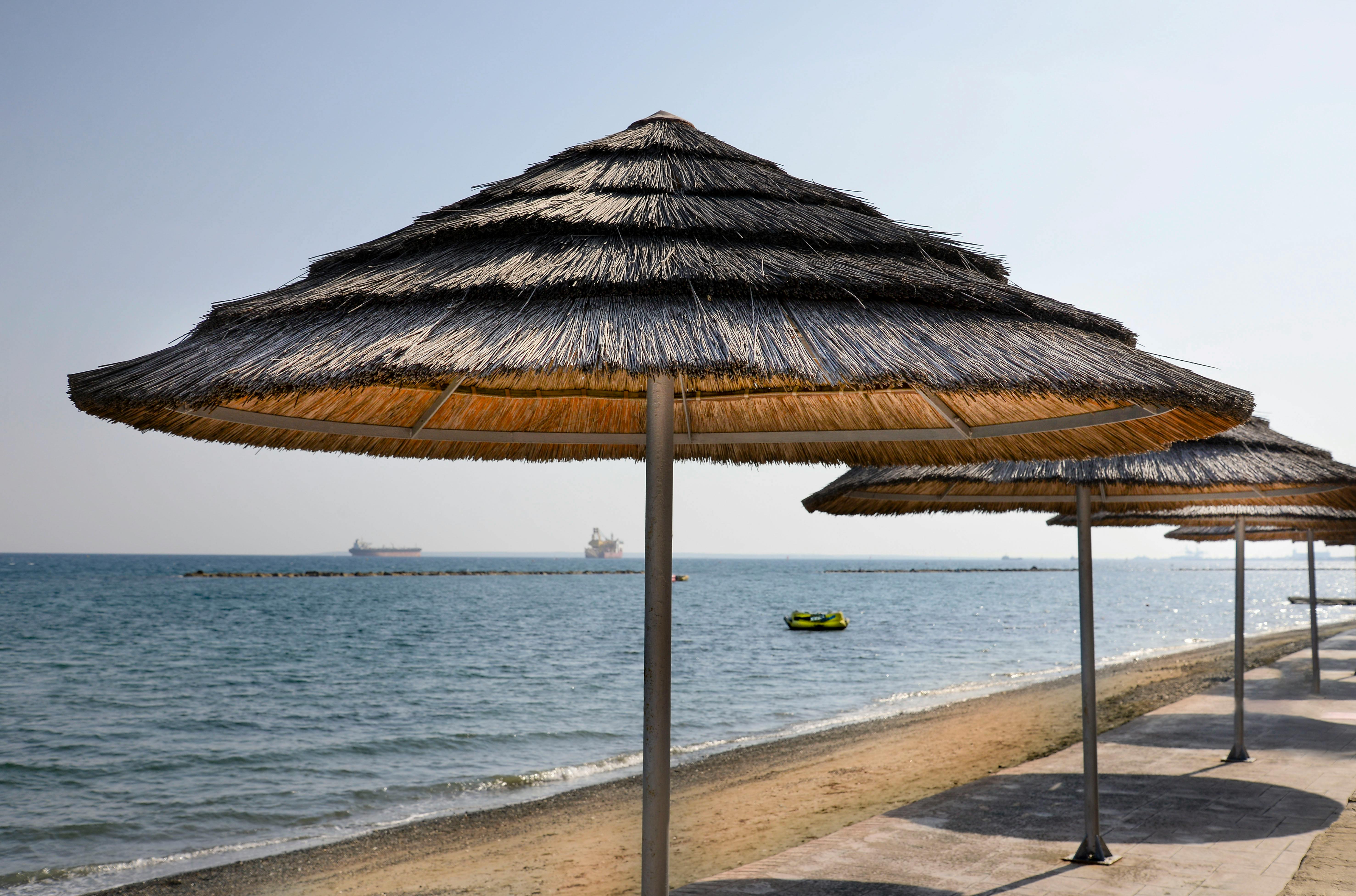 Tranquil beach setting with straw umbrellas along the Mediterranean coastline in Cyprus. - Photo by Elena Umyskova on Pexels