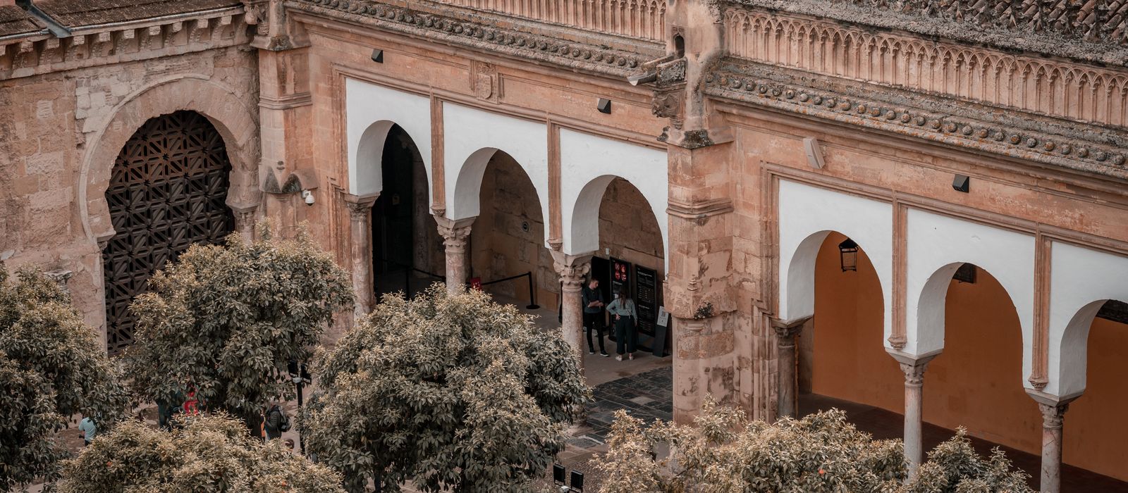 Aerial view of the historic Mosque-Cathedral of Córdoba with its iconic arches and surrounding trees.