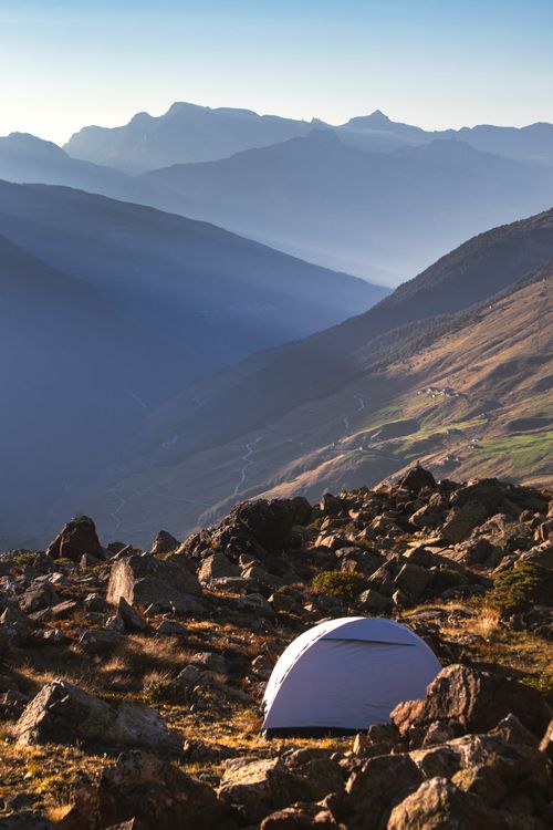 Free Serene mountain landscape with a tent amid rocky terrain during a sunny day. Stock Photo