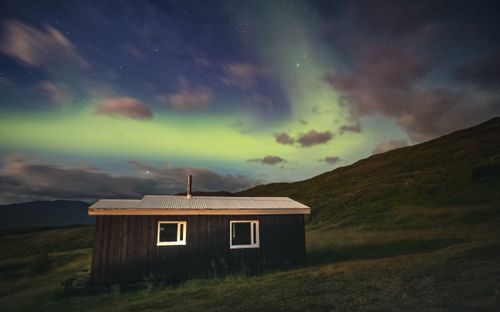 Free A serene cabin sits under the vibrant aurora borealis on a peaceful night. Stock Photo