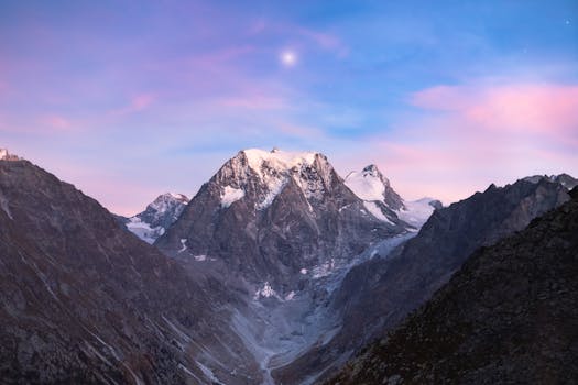 Breathtaking view of snow-covered mountains and valleys under a serene twilight sky.