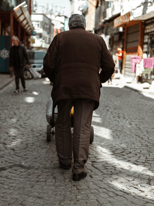 Man in Brown Jacket Pushing a Hand Truck