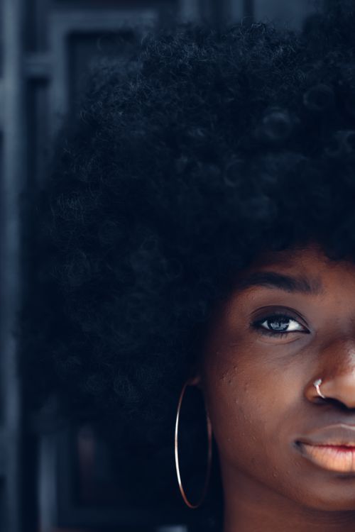 Free Artistic close-up of a black woman with afro hair, hoop earring, and nose piercing. Stock Photo