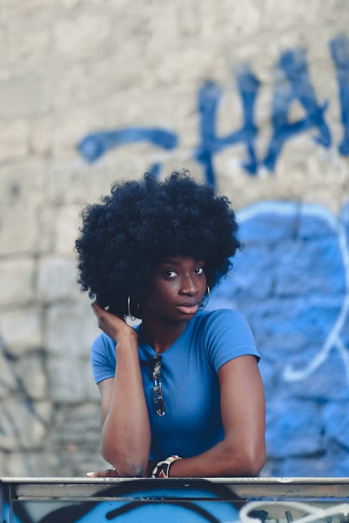 Woman with Curly Hair Leaning on a Railing with One Hand in Hair