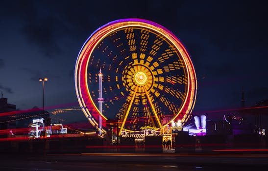 Captivating long exposure shot of an illuminated Ferris wheel at night in an urban carnival setting.